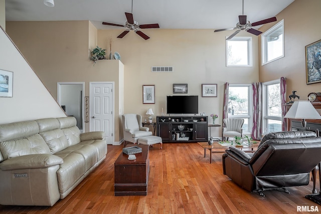 living room featuring hardwood / wood-style flooring, ceiling fan, and a high ceiling