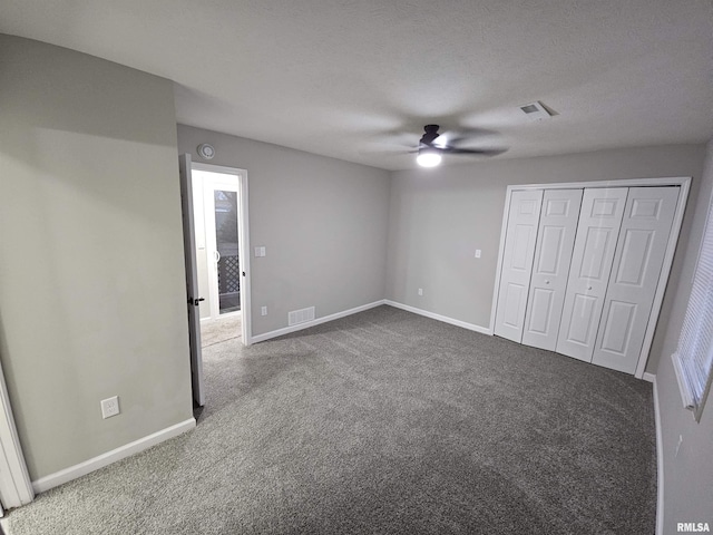 unfurnished bedroom with a textured ceiling, carpet floors, a closet, and ceiling fan