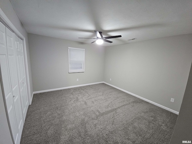 unfurnished bedroom featuring ceiling fan, dark carpet, and a closet