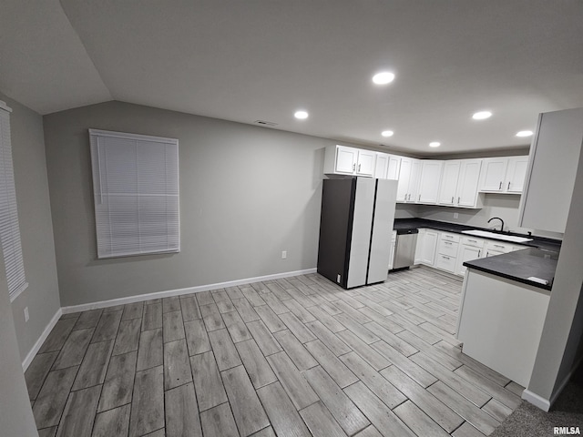 kitchen with fridge, stainless steel dishwasher, sink, and white cabinets