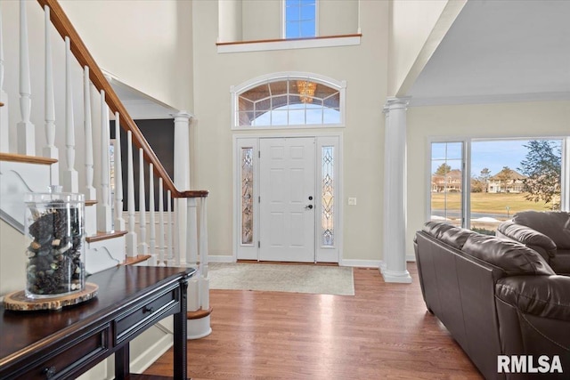 foyer featuring decorative columns, a towering ceiling, and hardwood / wood-style floors