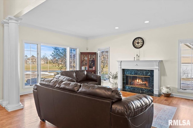 living room with ornate columns, ornamental molding, a fireplace, and light hardwood / wood-style flooring