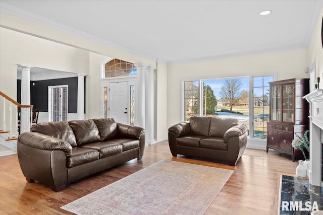 living room featuring ornate columns, ornamental molding, a premium fireplace, and hardwood / wood-style floors