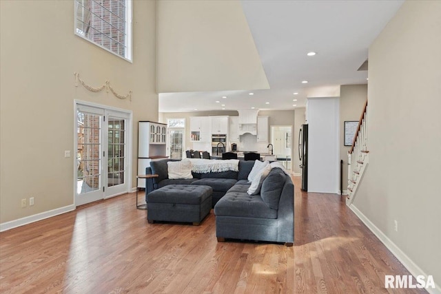 living room with sink, a towering ceiling, a wealth of natural light, and light wood-type flooring