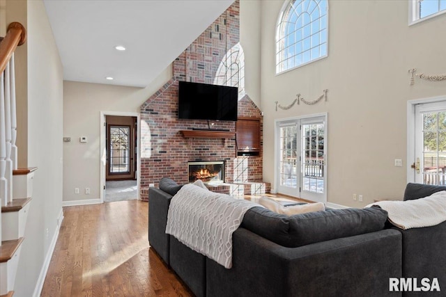 living room with hardwood / wood-style flooring, a fireplace, and a towering ceiling