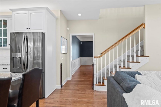 kitchen featuring white cabinetry, backsplash, light hardwood / wood-style floors, stainless steel refrigerator with ice dispenser, and light stone countertops