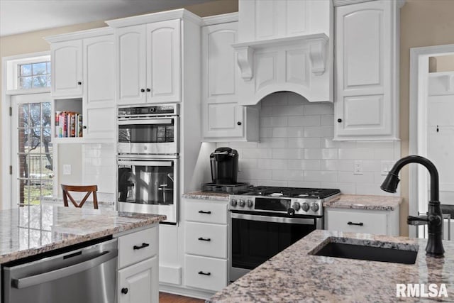 kitchen featuring light stone counters, appliances with stainless steel finishes, sink, and white cabinets