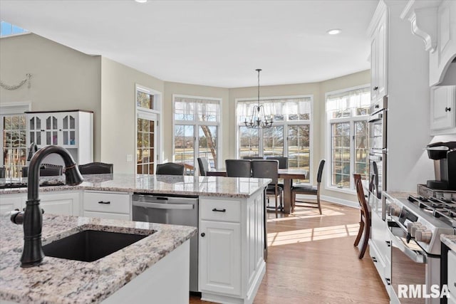 kitchen featuring white cabinetry, dishwasher, sink, and pendant lighting