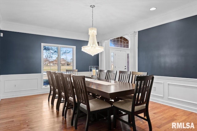 dining area with ornate columns, wood-type flooring, and crown molding