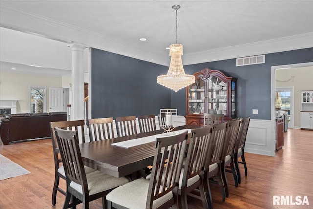 dining area with crown molding, hardwood / wood-style flooring, decorative columns, and a chandelier