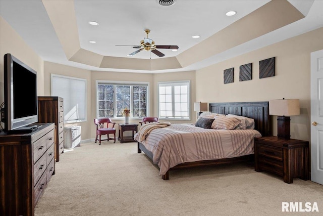 carpeted bedroom with a tray ceiling and ceiling fan