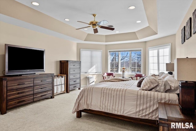 carpeted bedroom with a tray ceiling and ceiling fan