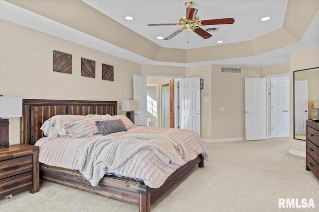 carpeted bedroom with a tray ceiling and ceiling fan