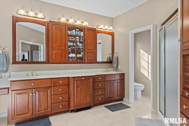 bathroom featuring a shower with door, vanity, and toilet