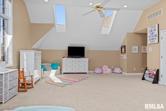 playroom featuring vaulted ceiling with skylight, light colored carpet, and ceiling fan