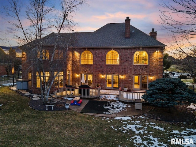 snow covered property with a wooden deck and a yard