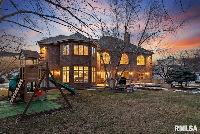 back house at dusk with a lawn and a playground