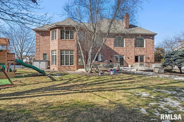 rear view of house featuring a wooden deck, a yard, and a playground