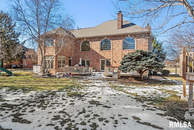 snow covered house with a yard and a deck