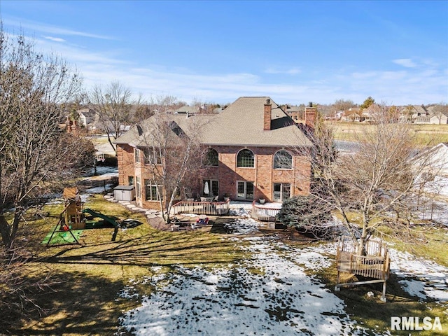 back of property with a deck with water view, a yard, and a playground