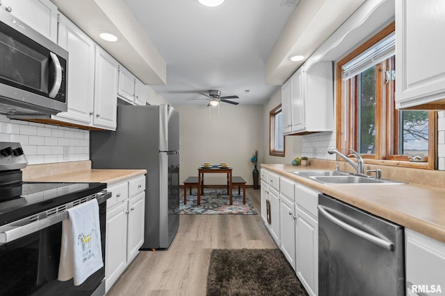 34187 E 6th Rd, Pawnee, IL 62558 - kitchen with white cabinets, light wood-style flooring, a sink, light countertops, and appliances with stainless steel finishes
