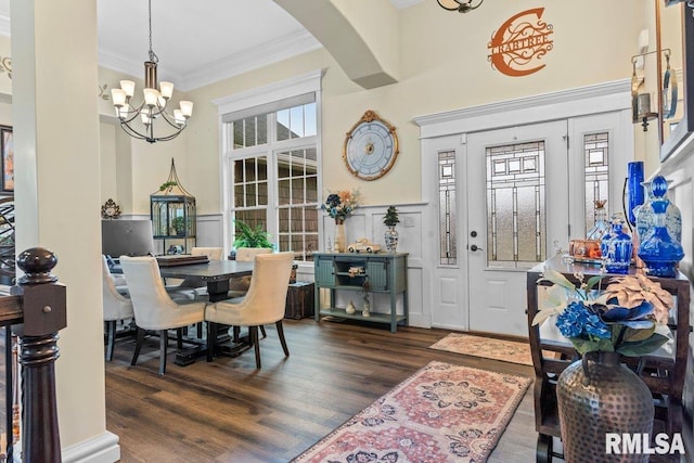 interior space featuring dark wood-type flooring, a healthy amount of sunlight, ornamental molding, and a notable chandelier