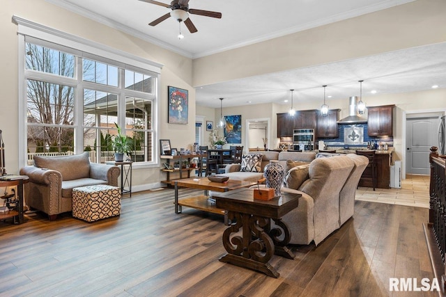 living room featuring hardwood / wood-style flooring, ceiling fan, and crown molding