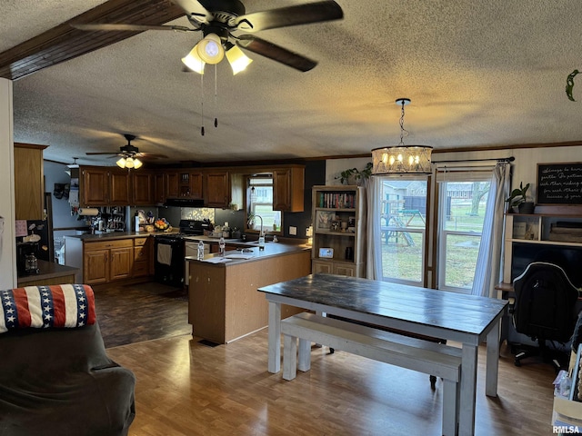 kitchen featuring dark hardwood / wood-style floors, hanging light fixtures, ornamental molding, kitchen peninsula, and black / electric stove