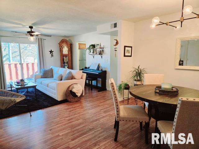 living room featuring dark wood-type flooring and ceiling fan with notable chandelier