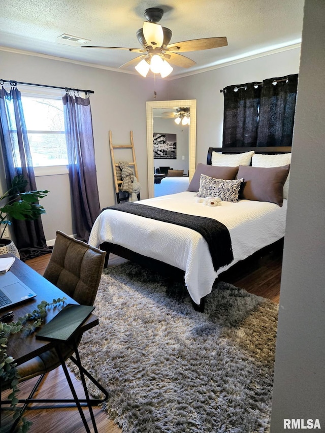 bedroom with ceiling fan, crown molding, wood-type flooring, and a textured ceiling