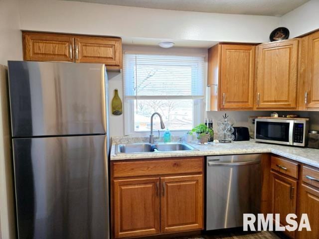 kitchen with sink, light stone countertops, and appliances with stainless steel finishes