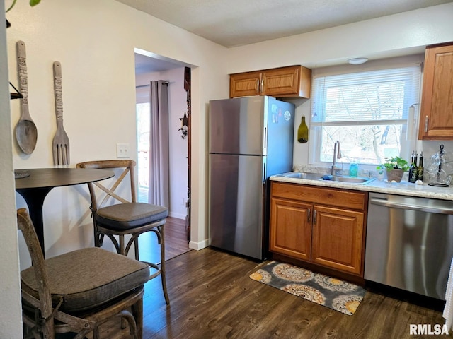 kitchen with stainless steel appliances, sink, dark wood-type flooring, and light stone counters