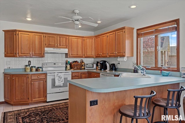 kitchen with a ceiling fan, a sink, a peninsula, white electric range oven, and under cabinet range hood