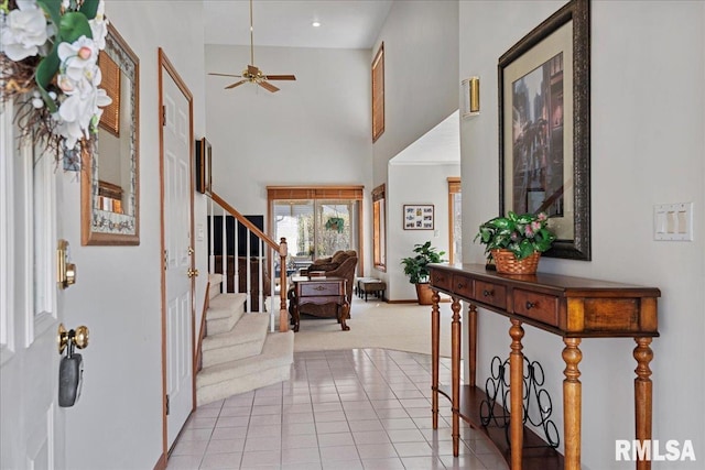 foyer with light tile patterned flooring, a towering ceiling, and ceiling fan