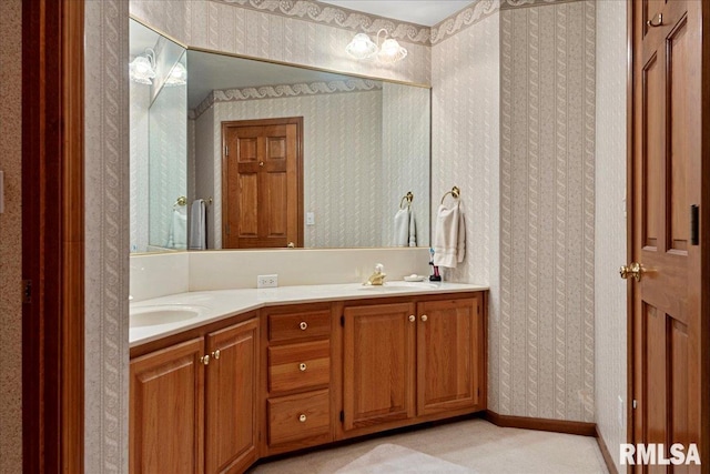 bathroom with double vanity, a sink, and wallpapered walls