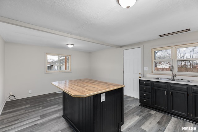 kitchen with dark wood-type flooring, a center island, sink, and a textured ceiling