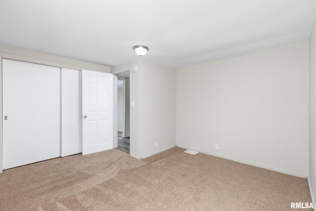 unfurnished bedroom featuring light colored carpet and a closet