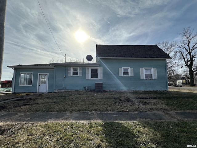 rear view of property with central AC unit and a yard