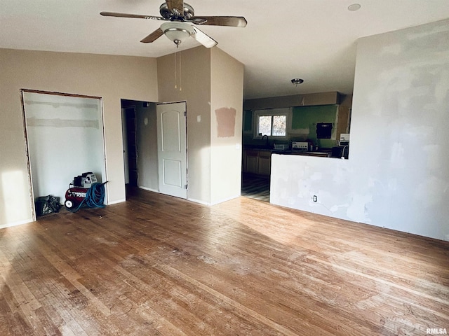 unfurnished living room featuring hardwood / wood-style flooring, ceiling fan, and vaulted ceiling