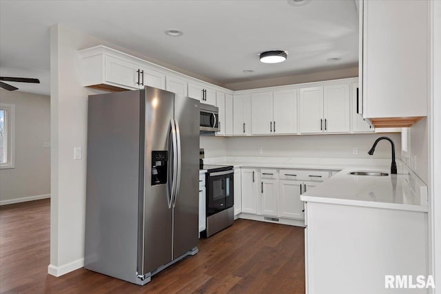 kitchen with sink, ceiling fan, appliances with stainless steel finishes, white cabinets, and dark hardwood / wood-style flooring