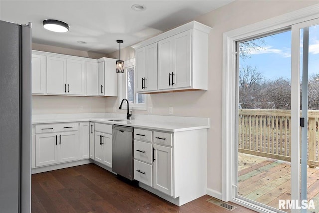 kitchen with pendant lighting, sink, appliances with stainless steel finishes, white cabinetry, and dark hardwood / wood-style flooring