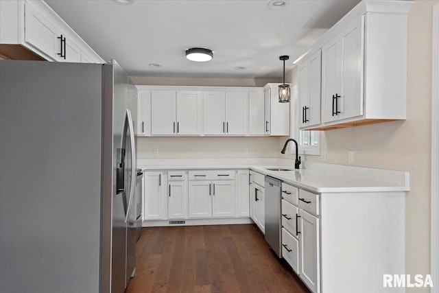 kitchen featuring sink, appliances with stainless steel finishes, dark hardwood / wood-style floors, white cabinets, and decorative light fixtures