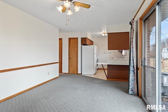 interior space with white refrigerator, sink, light colored carpet, and ceiling fan