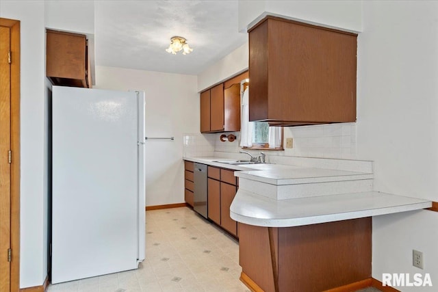 kitchen with white refrigerator, stainless steel dishwasher, sink, and decorative backsplash