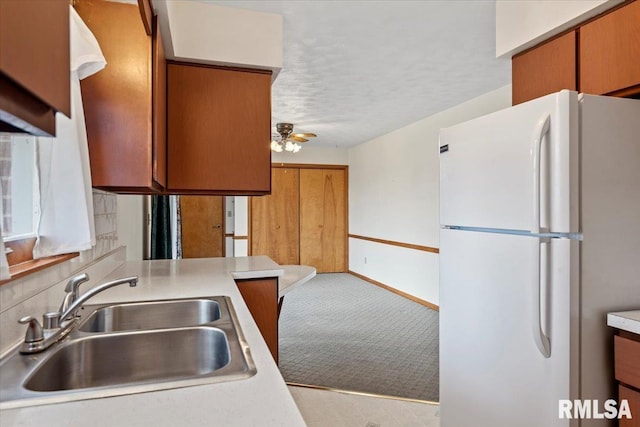 kitchen with sink, white refrigerator, ceiling fan, light carpet, and a textured ceiling