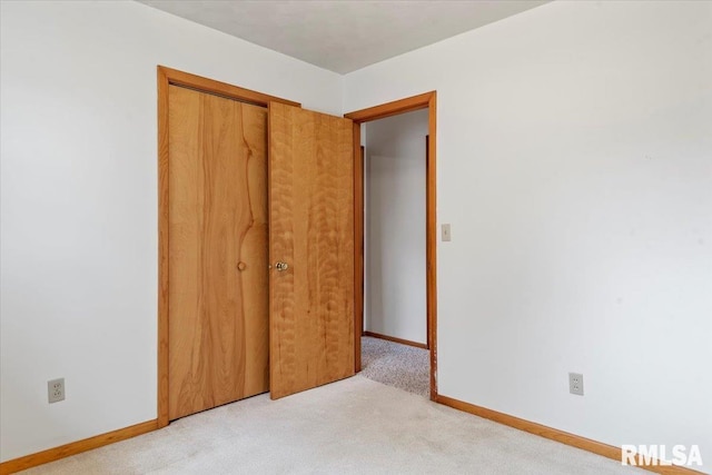 unfurnished bedroom featuring light colored carpet and a closet