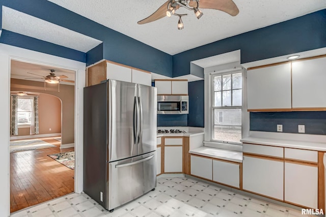 kitchen featuring a healthy amount of sunlight, ceiling fan, stainless steel appliances, and white cabinets