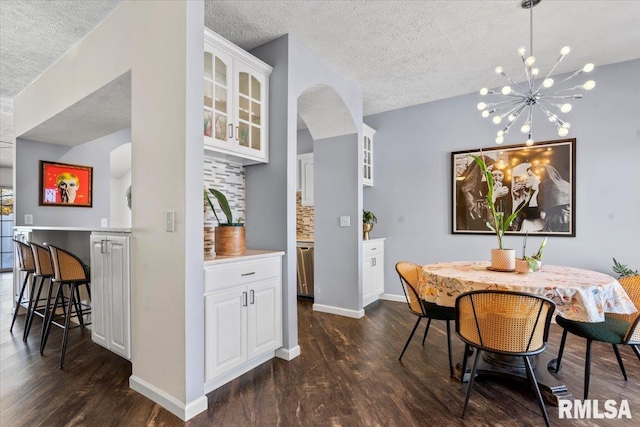 dining space featuring dark hardwood / wood-style flooring, a notable chandelier, and a textured ceiling