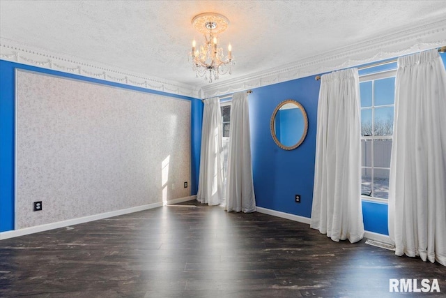 spare room featuring dark hardwood / wood-style flooring, a notable chandelier, and a healthy amount of sunlight