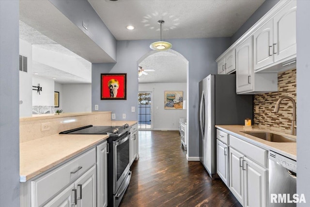 kitchen with stainless steel appliances, white cabinetry, hanging light fixtures, and sink